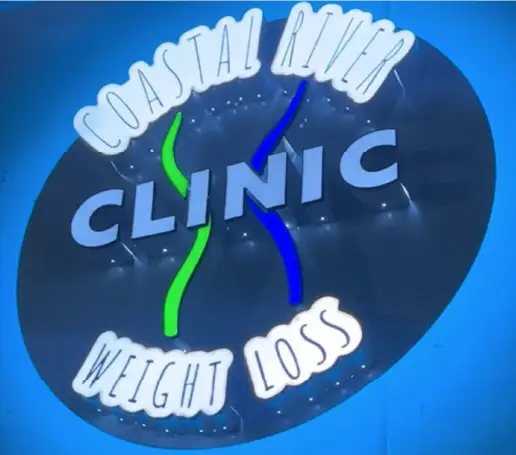 Coastal River Weight Loss Clinic circular storefront sign illuminated at night